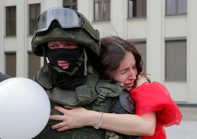 A participant embraces a member of Belarusian Interior Ministry troops, who stands guard during an opposition demonstration to protest against police violence and to reject the presidential election results near the Government House in Independence Square in Minsk, Belarus on August 14, 2020. (Photo by Vasily Fedosenko/Reuters)