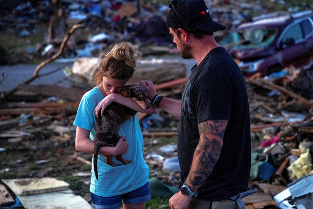 A young girl carries her dog as they reunite in the Sunshine Hills neighborhood after a series of tornadoes hit Laurel County, in London, Kentucky on May 18, 2025. (Photo by Seth Herald/Reuters)