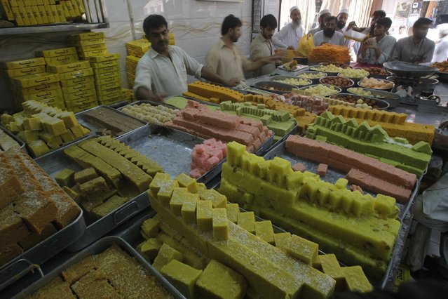 People buy sweets for the upcoming Muslim holiday of Eid al-Adha, in Peshawar, Pakistan, Monday, September12, 2016. Pakistanis will celebrate the Eid al-Adha, or the Feast of the Sacrifice, on Tuesday to mark the willingness of the Prophet Ibrahim – Abraham to Christians and Jews – to sacrifice his son. During the holiday Muslims slaughter sheep and cattle, distribute part of the meat to the poor and eat the rest. (Photo by Mohammad Sajjad/AP Photo)