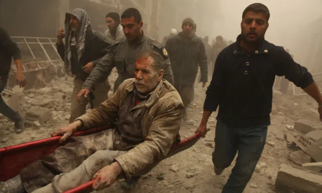 Civil defense team members and civillians rescue a wounded man from debris of a building after war planes belonging to Assad regime carried out airstrike to Zamalka town of besieged Eastern Ghouta in Damascus, Syria on February 6, 2018. At least 30 civilians were killed after the attack. (Photo by Kahled Al Adil/Anadolu Agency/Getty Images)