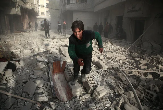 A Syrians youth runs following an air strike in the rebel- held enclave of Arbin in the Eastern Ghouta near Damascus on February 8, 2018. The death toll from Syrian regime air strike on the rebel- held enclave of Eastern Ghouta near Damascus rose to 36, a monitor said. Ten children and seven women were among today' s victims, bringing to 185 the number of civilians killed over the past four days, said Rami Abdel Rahman, head of the Britain- based Observatory. (Photo by Amer Almohibany/AFP Photo)