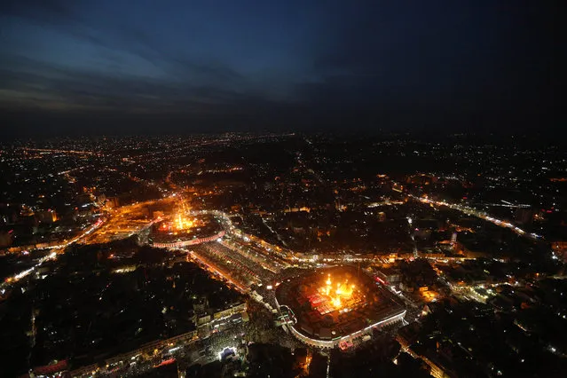 This aerial photo shows Shiite faithful pilgrims gathered between, the holy shrine of Imam Hussein, bottom, and the holy shrine of Imam Abbas, top, during preparations for the Muslim holiday of Ashoura in the Shiite holy city of Karbala, 50 miles (80 kilometers) south of Baghdad, Iraq, Friday, October 23, 2015. Ashoura is the tenth day of the Islamic month of Muharram, commemorating the Battle of Karbala in the 7th century when Imam Hussein, a grandson of Prophet Muhammad, was killed in present-day Iraq. (Photo by Hadi Mizban/AP Photo)