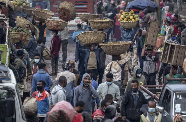 Traders carry baskets of vegetables through muddy pathways in Atkilt Tera, the largest open-air vegetable market, in the capital Addis Ababa, Ethiopia Thursday, September 10, 2020. Ethiopians are stocking up on food on new year's eve of the Ethiopian calendar ahead of the holiday of “Enkutatash”, the first day of the new year that is traditionally associated with the return of the Queen of Sheba to Ethiopia some 3,000 years ago. (Photo by Mulugeta Ayene/AP Photo)