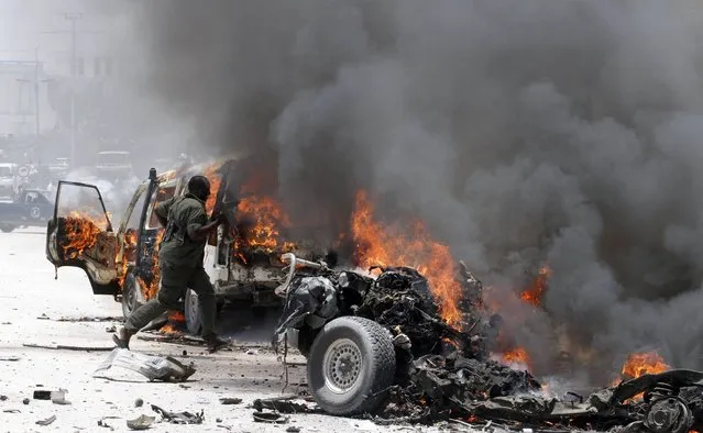 A policeman runs through burning vehicles at the scene of an explosion near the presidential palace in Somalia's capital Mogadishu, March 18, 2013. A car bomb exploded near the presidential palace in the Somali capital Mogadishu on Monday, killing at least 10 people in a blast that appeared to target senior government officials, police said. (Photo by Feisal Omar/Reuters)