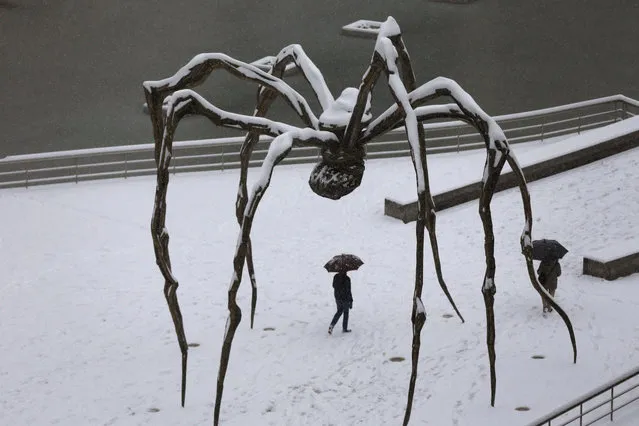 A man walks under snow-covered Louise Bourgeois' Maman (Ama) bronze sculpture in front of Guggenheim Bilbao Museum during a snowstorm in Bilbao, the Basque Country, northern Spain, 28 February 2018. (Photo by Luis Tejido/EPA/EFE)