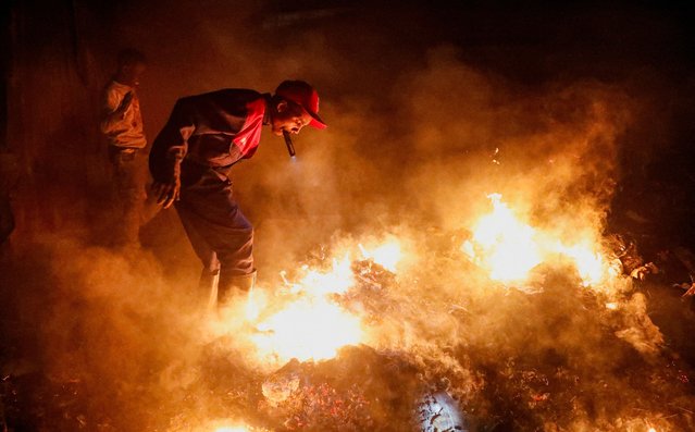 A man uses a spotlight to salvage belongings during a fire outbreak at iron-sheet homes in the Grogon village of Huruma district in Nairobi, Kenya on August 10, 2025. (Photo by Thomas Mukoya/Reuters)