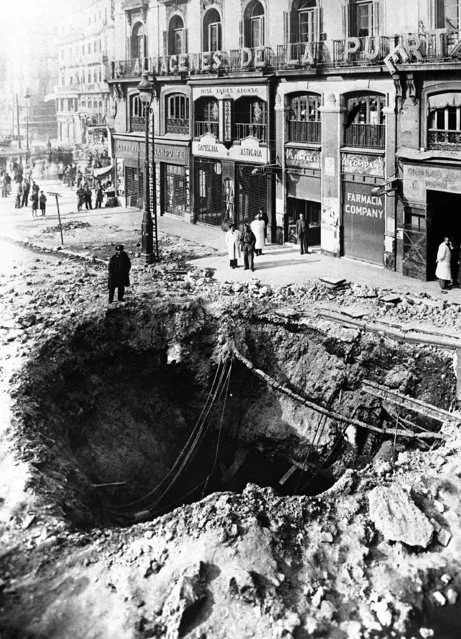 Although the defending forces of Madrid would seem to be gaining the upper hand, the capital is still being bombed and shelled almost every day, and the destruction of buildings and streets continues. A huge crater formed in a Madrid street by an aerial bomb dropped during a Nationalist air raid, on March 23, 1937. (Photo by AP Photo)