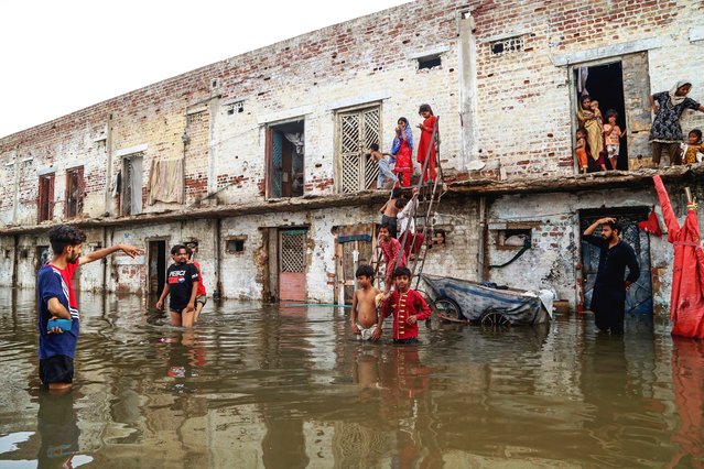 Residents gather outside their houses, which have been submerged by floodwaters following heavy monsoon rains in Hyderabad, Sindh province on July 15, 2025. Monsoon rains in Pakistan have been linked to more than 110 deaths, including dozens of children, since they arrived in late June, according to government figures released on July 14. (Photo by Husnain Ali/AFP Photo)