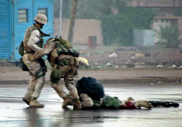 U.S. Marine platoon Gunnery Sergeant, Ryan P. Shane (C), from the 1st Battalion of the 8th Marine Regiment and another member of 1/8 pull a fatally wounded comrade to safety while under fire during a military operation in Falluja, December 17, 2004. Seconds later Sgt. Shane was also injured by nearby enemy fire. (Photo by Cpl. Joel A. Chaverri/Reuters/USMC)