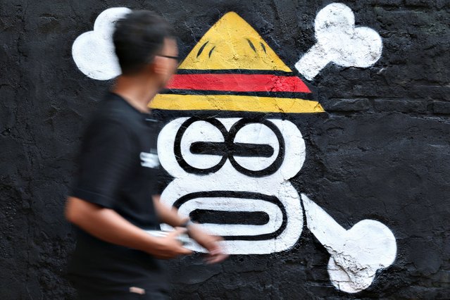 Kemas Muhammad Firdaus, 28, walks past a mural depicting a Jolly Roger from the popular Japanese anime and manga series “One Piece” in Bekasi, West Java province, Indonesia, on August 7, 2025. (Photo by Ajeng Dinar Ulfiana/Reuters)