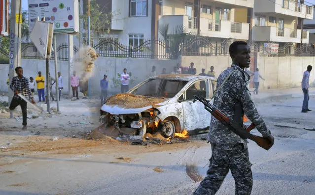 A Somali soldier attends the scene after a bomb attack near the office of the International Committee of the Red Cross in Mogadishu, Somalia Wednesday, March 28, 2018. Somali police say at least three people are wounded after the bomb which was attached to their vehicle exploded. (Photo by Mohamed Sheikh Nor/AP Photo)