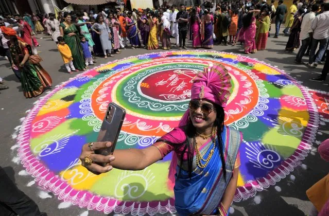 A woman dressed in traditional attire takes a selfie during a procession to mark Gudi Padwa, or the Marathi new year, in Mumbai, India, Saturday, April 2, 2022. (Photo by Rajanish Kakade/AP Photo)