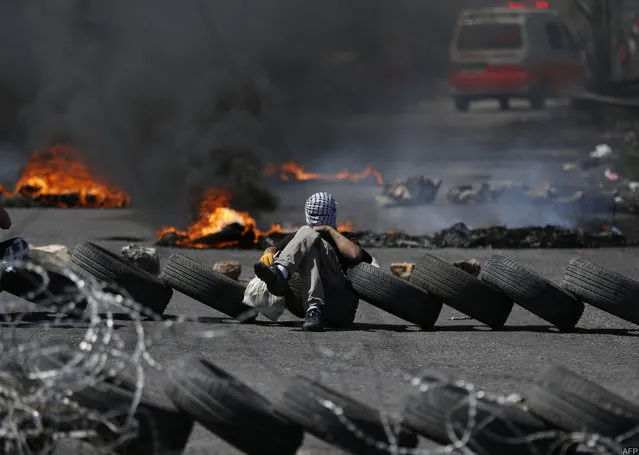Palestinian men burn tyres during a protest in the West Bank city of Ramallah on April 6, 2018. Clashes erupted on the Gaza-Israel border Friday, AFP journalists said, a week after similar demonstrations led to violence in which Israeli force killed 19 Palestinians, the bloodiest day since a 2014 war. Palestinians burned tyres and threw stones at Israeli soldiers over the border fence, who responded with tear gas and live fire, the correspondents said. (Photo by Abbas Momani/AFP Photo)