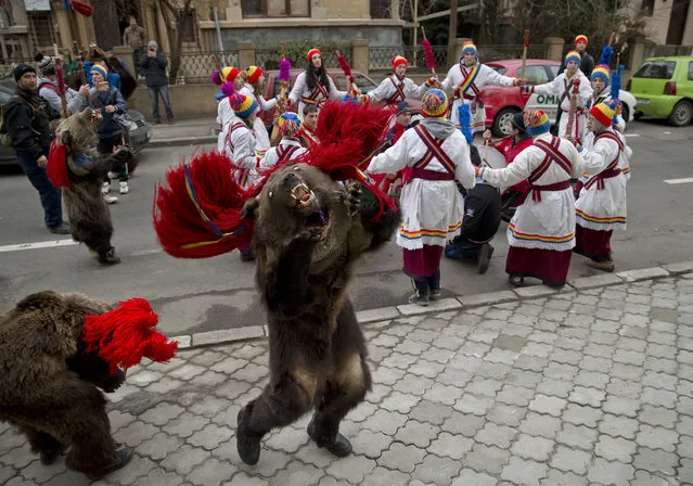 Children from Dofteana, northern Romania, some wearing bear furs, dance while performing a holiday season ritual in Bucharest, Romania, Tuesday, December 23, 2014. In pre-Christian rural traditions, dancers wearing colored costumes or animal furs, touring house to house in villages singing and dancing to ward off evil. (Photo by Vadim Ghirda/AP Photo)