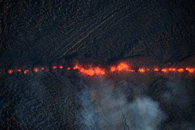 An aerial view shows fissure 17 continuing to erupt, creating wide, a mile long flow of lava that now threatens homes, property, and two major thoroughfares in Pahoa, Hawaii, USA, 14 May 2018. Ground cracks and seismicity indicate a continued easterly migration. Eighteen fissures have been reported in and around Leilani Estate. Kilauea is the most active volcano on the Hawaii's Big Island and some experts predict the volcanic activity could cause a massive explosion in the coming weeks. (Photo by Bruce Omori/Paradise Helicopters/EPA/EFE)