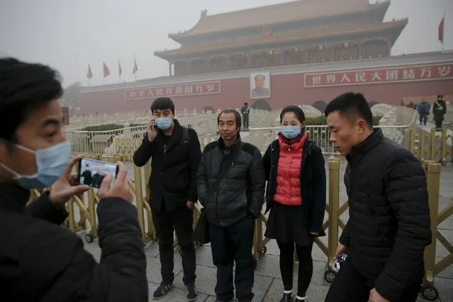 People wearing protective masks have their picture taken near the Tiananmen Gate on an extremely polluted day as hazardous, choking smog continues to blanket Beijing, China December 1, 2015. (Photo by Damir Sagolj/Reuters)