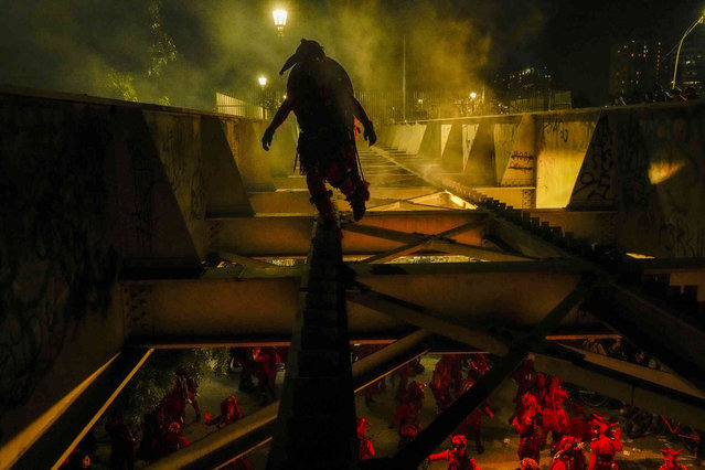 Performers known as the Red Devils of Victor Jara dance on the Bulnes Bridge during a vigil marking the anniversary of the 1973 military coup that toppled the government of President Salvador Allende, in Santiago, Chile, Wednesday, September 11, 2024. Political opponents were executed on the bridge in the early years of the dictatorship. (Photo by Esteban Felix/AP Photo)