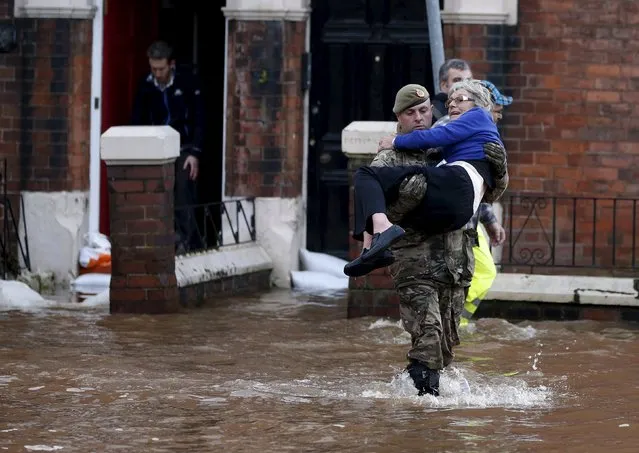 A soldier carries a woman from a flooded house on a residential street in Carlisle, Britain December 6, 2015. (Photo by Phil Noble/Reuters)