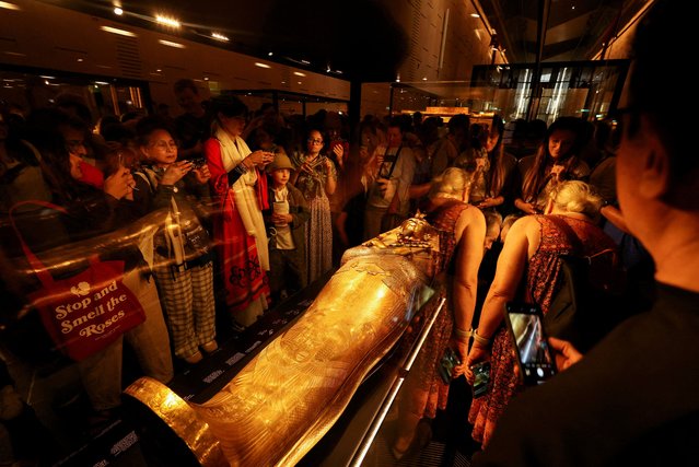 Visitors look at the golden coffin of ancient Egyptian Pharaoh Tutankhamun during the first day for visitors, after the official opening of the Grand Egyptian Museum (GEM), near the Giza pyramid complex, in Giza, Egypt, on November 4, 2025. (Photo by Mohamed Abd El Ghany/Reuters)