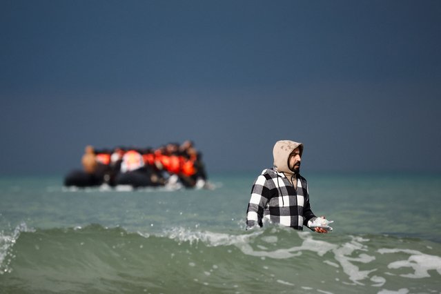A migrant holds a smartphone as he heads towards an inflatable dinghy in an attempt to cross the English Channel, on the beach of the Slack dunes in Wimereux, France, on September 4, 2024. (Photo by Benoit Tessier/Reuters)
