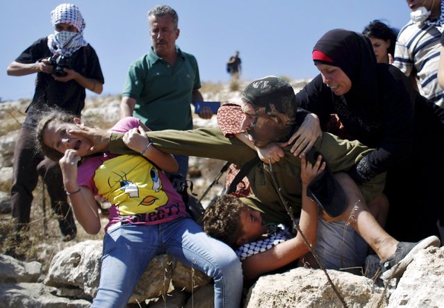 Palestinians try to prevent an Israeli soldier from detaining a boy during a protest against Jewish settlements in the West Bank village of Nabi Saleh, near Ramallah August 28, 2015. (Photo by Mohamad Torokman/Reuters)