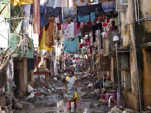 A woman walks in an alley filled with mud and debris to collect relief goods as clothes are hung out to dry after flood waters receded in Chennai, India, December 7, 2015. (Photo by Anindito Mukherjee/Reuters)