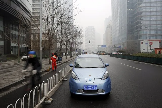 A Roewe E50 electric car is parked next to a street as a bicycle travels past, amid heavy smog, after the city issued its first ever "red alert" for air pollution in Beijing, China, December 9, 2015. (Photo by Damir Sagolj/Reuters)