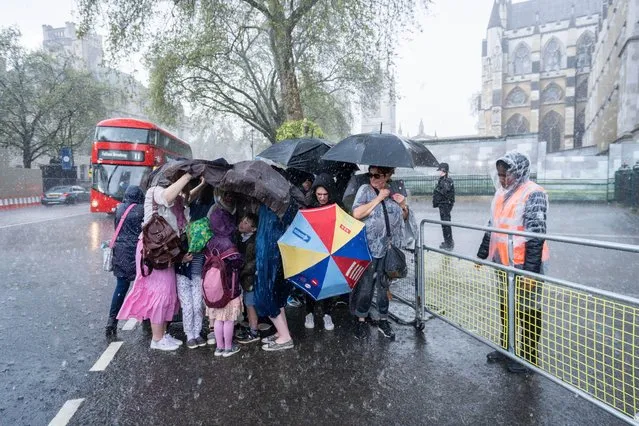 Pedestrians and royal fans are caught in a heavy downpour in Westminster in London on May 5, 2023, a day before the coronation of King Charles III, the biggest ceremonial event staged in the capital for 70 years. (Photo by ghazzal/Alamy Live News)