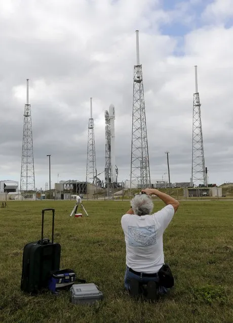 A photographer works as a remodeled version of the SpaceX Falcon 9 rocket rests on its pad as it is prepared for launch at the Cape Canaveral Air Force Station on the launcher's first mission since a June failure in Cape Canaveral, Florida December 20, 2015. The rocket carries a payload of eleven satellites owned by Orbcomm, a New Jersey-based communications company. (Photo by Joe Skipper/Reuters)