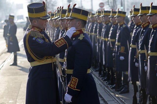 The commanding officer of the Presidential Honor Guard adjusts a soldiers uniform during an official commemoration ceremony dedicated to those who died during the 1989 popular uprising, at the Heroes of the Revolution Cemetery in Bucharest, 21 December 2015. Up to 1100 people died during the 1989 uprising against communist rule of Romania. (Photo by Robert Ghement/EPA)