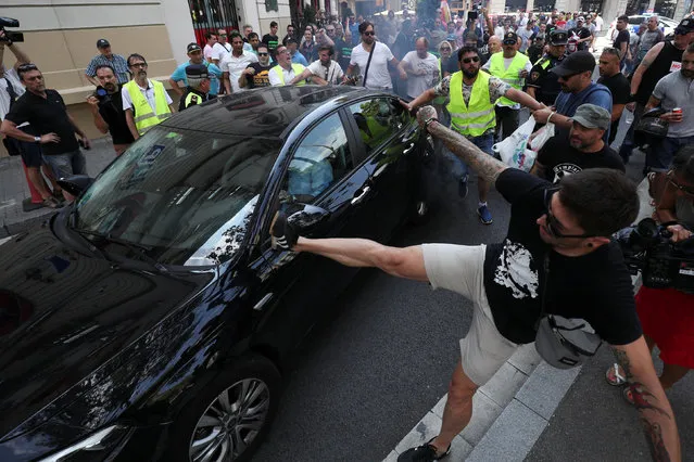 Taxi drivers kick at a car they identified as a Uber vehicle during a strike against what they say is unfair competition from ride-hailing and car-sharing services such as Uber and Cabify in Barcelona, Spain, July 25, 2018. (Photo by Albert Gea/Reuters)