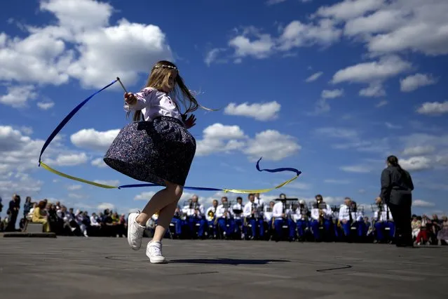 A girl dances as she attends a concert of an orchestra during Kyiv Day celebrations in Kyiv, Ukraine, Sunday, May 29, 2022. Ukraine's capital celebrates the anniversary of its foundation every last Sunday of May. (Photo by Natacha Pisarenko/AP Photo)