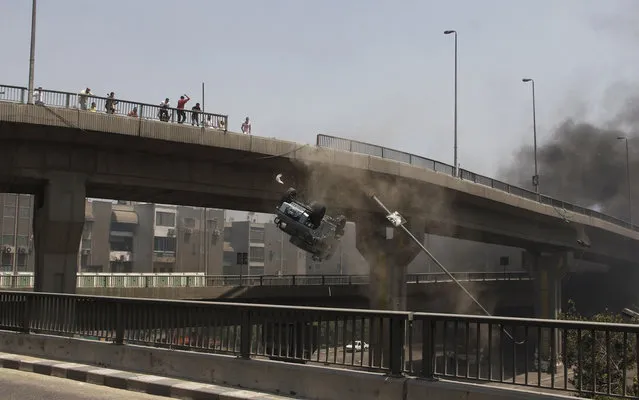 A police vehicle is pushed off of the Sixth of October Bridge in Cairo on August 14, 2013. (Photo by Sabry Khaled/AP Photo/El Shorouk Newspaper)