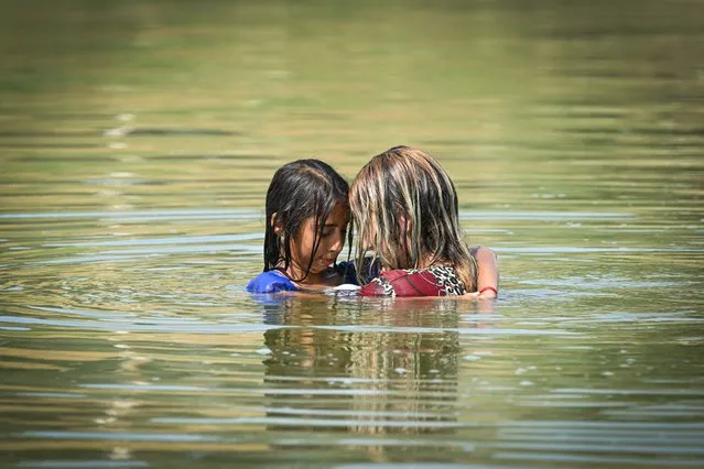 A woman and a young girl are seen in the water of an abandoned irrigation station in the Frasinet village in the Calarasi county, south-east of Bucharest, Romania, on July 25, 2023. A heat wave on July 25, 2023 has risen the temperatures in southern Romania up to 42 degrees Celsius. (Photo by Daniel Mihailescu/AFP Photo)