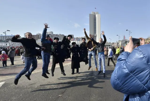 People, including Russian navy sailors, jump while posing for a picture during celebrations for the Defender of the Fatherland Day in the far eastern city of Vladivostok February 23, 2015. (Photo by Yuri Maltsev/Reuters)