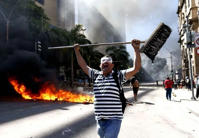 A man holds a broom as he shouts during clashes with police outside the state legislature during a protest against austerity measures being discussed in the chamber, in Rio de Janeiro, Brazil, Tuesday, December 6, 2016. Legislators were voting on measures to address the state’s deepening financial crisis, in which thousands of state employees and retirees have not been paid or have been paid months late. (Photo by Silvia Izquierdo/AP Photo)