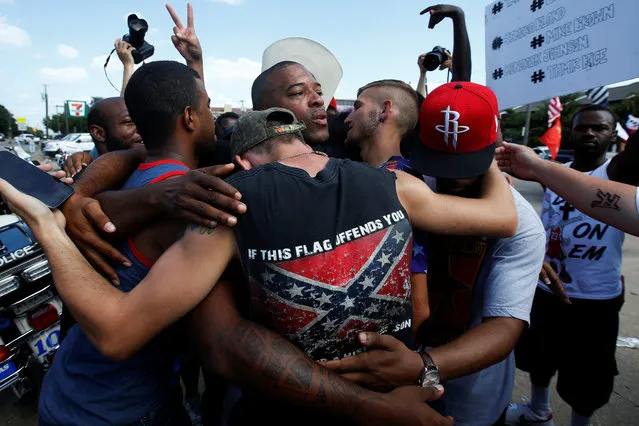 People, including a man wearing a confederate flag, hug after taking part in a prayer circle after a Black Lives Matter protest following the multiple police shootings in Dallas, Texas, July 10, 2016. (Photo by Carlo Allegri/Reuters)