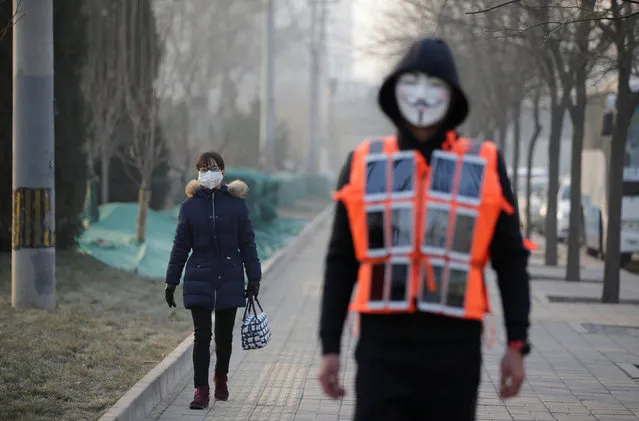 A woman is pictured behind artist Liu Bolin wearing a vest with 24 mobile phones as he walks along a street during a live broadcast of air pollution in the city on the fourth day after a red alert was issued for heavy air pollution in Beijing, China, December 19, 2016. (Photo by Jason Lee/Reuters)