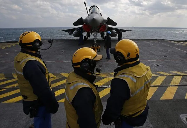 “Yellow dogs” fly deck directors watch as a Rafale fighter jet is brought up on an elevator to the flight deck aboard France's Charles de Gaulle aircraft carrier in the Gulf, January 29, 2016. (Photo by Philippe Wojazer/Reuters)