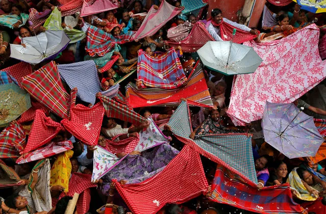 Hindu devotees hold up clothes and umbrellas to receive rice as offerings being distributed by a temple authority on the occasion of the Annakut festival in Kolkata, India, November 8, 2018. (Photo by Rupak De Chowdhuri/Reuters)