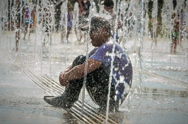 A man refreshes seating on a water-jets fountain in Moscow, Russia, 23 June 2021. The temperature exceeded 36 degrees Celsius in Moscow. The weather in Moscow broke the temperature record high of the day, held since 1948, when meteorologists recorded +33.6. (Photo by Sergei Ilnitsky/EPA/EFE)