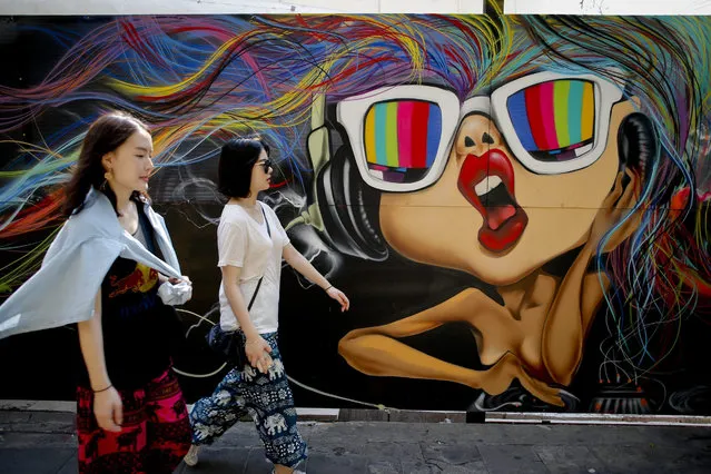 Two women walk in front of a colorful graffiti painted on a wall in Bangkok, Thailand, 03 February 2016. Thailand's economy is forecast to grow at 3.7 percent in 2016 revised down from earlier projected of 3.8 percent driven by the private consumption and investment as well as government stimulus measures and billion-dollar investment in infrastructure project, according to the Fiscal Policy Office. (Photo by Diego Azubel/EPA)