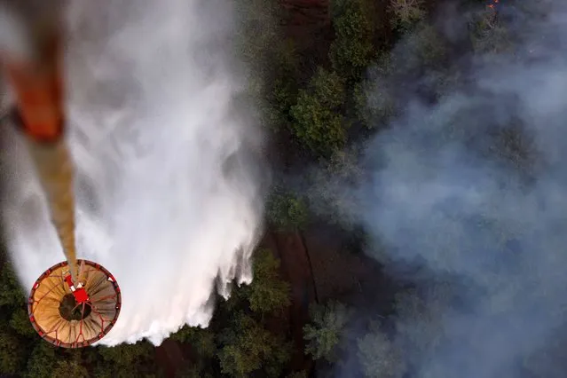 A firefighting helicopter drops water as smoke rises from a wildfire near Marmaris, Turkey on August 3, 2021. (Photo by Umit Bektas/Reuters)