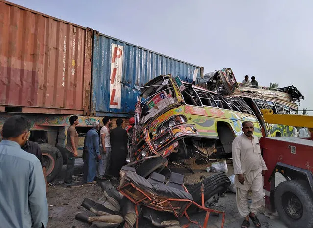 In this handout photo released by Punjab Province's Emergency Service Rescue 11222, shows residents and rescue workers at the site of a deadly bus accident near Dera Ghazi Khan, Pakistan, Monday, July 19, 2021. The speeding bus carrying mostly laborers traveling home for a major Muslim holiday rammed into a container truck on a busy highway in central Pakistan, killing and injuring dozens, police and rescue officials said. (Photo by Emergency Service Rescue 1122 via AP Photo)