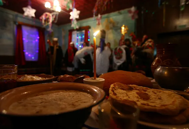 A candle and food are seen on a table as people celebrate the pagan rite called “Kolyadki” and mark the New Year, according to the Julian calendar on January 13, in the village of Vosava, Belarus January 13, 2017. (Photo by Vasily Fedosenko/Reuters)