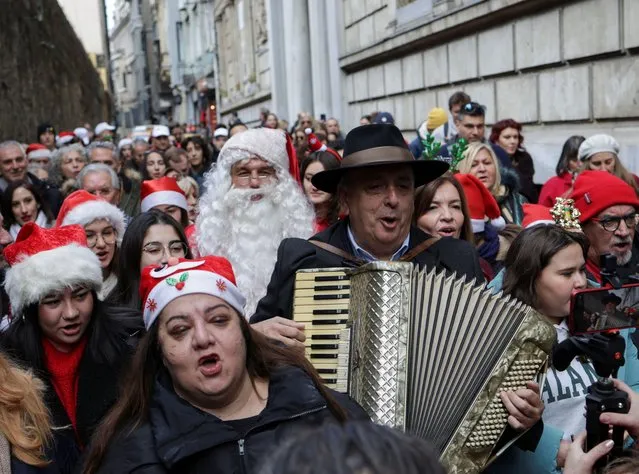 Zografyon Greek High School principal Yani Demircioglu plays an accordion, accompanied by school children and members of Greek Orthodox community, as they tour the streets of Beyoglu during a Christmas celebration in central Istanbul, Turkey on December 24, 2023. (Photo by Murad Sezer/Reuters)