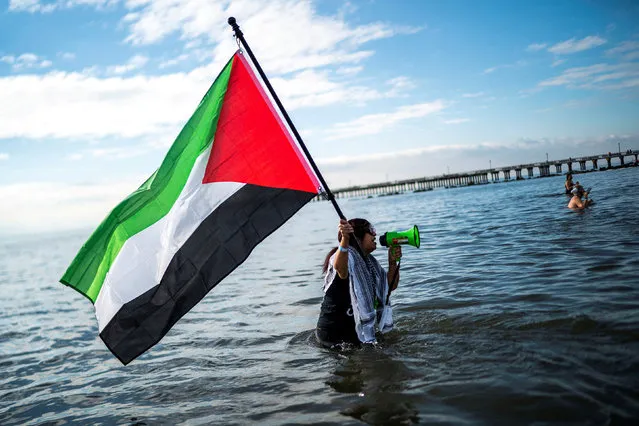 A woman holding a a Palestinian flag walks in the Atlantic Ocean during the annual Coney Island Polar Bear Club New Year's Day plunge in Brooklyn, New York on January 1, 2024. (Photo by Eduardo Munoz/Reuters)