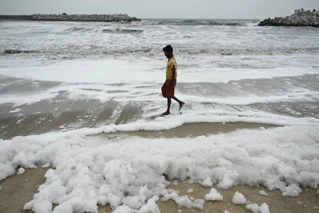 A man stands near the polluted sea water laden with foam at the Marina Beach in Chennai on January 8, 2024. (Photo by R. Satish Babu/AFP Photo)