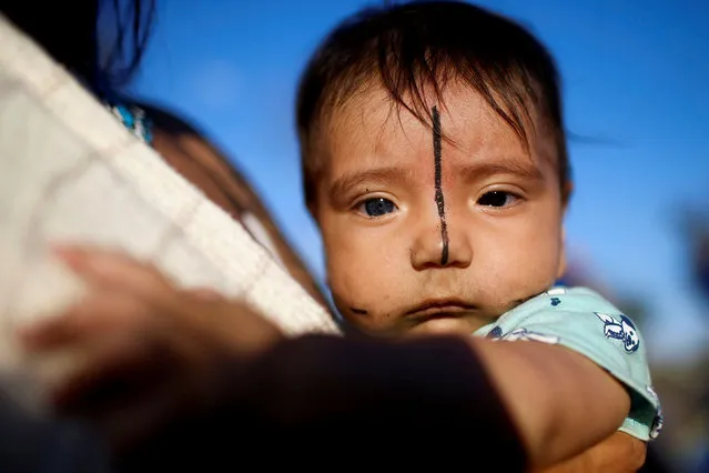 A Kayapo child looks on from his mother's lap during the camp Luta pela Vida (Struggle for Life), during a demonstration in defence of local indigenous people, in Brasilia, Brazil on August 23, 2021. (Photo by Adriano Machado/Reuters)