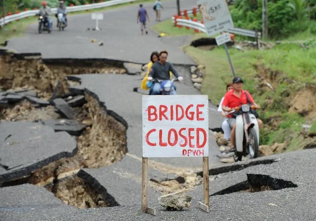 Motorists cross a damaged road destroyed at the height of the powerful earthquake in Guihulngan town, Negros Oriental province, central Philippines on February 9, 2012. (Photo by Ted Aljibe/AFP Photo)